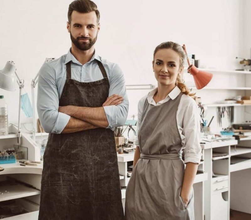 business-for-a-couple-portrait-of-smiling-couple-in-aprons-standing-at-their-jewelry-workshop-and.jpg